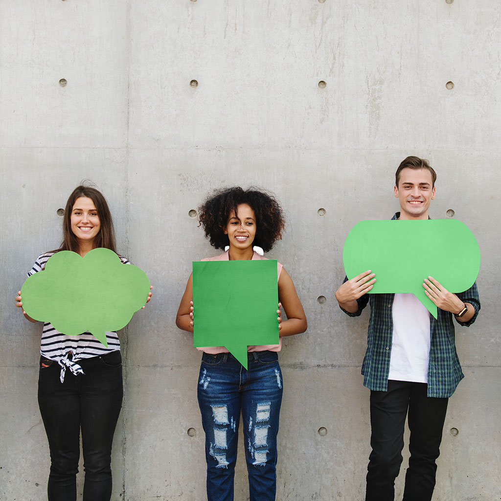 3 jóvenes muestran carteles verdes en forma de bocadillos.